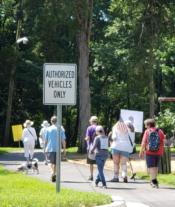 Greenbelters carrying Pro-democracy signs and an 
American flag toward the Spellman Overpass on Independence Day